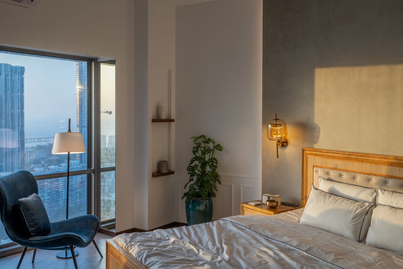 Luxurious bedroom with a minimalist design, featuring a wooden headboard, soft bedding, and a cozy reading nook.